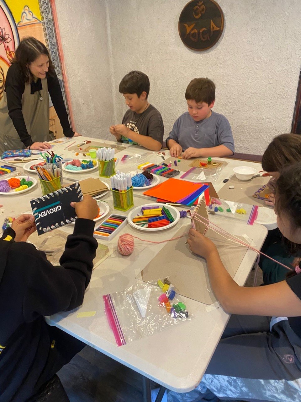 Niños y adultos haciendo manualidades en la mesa del taller