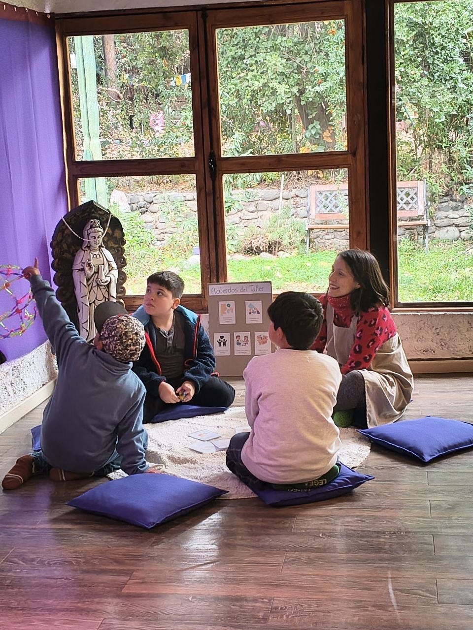 Grupo de niños sentados en el piso conversando con la tallerista